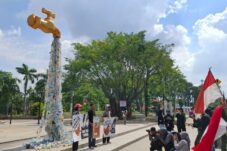 Sejumlah aktivis lingkungan berunjuk rasa dengan membawa kran raksasa berisi sampah yang mengalir di depan alun-alun Sidoarjo, Senin (19/5/2025) (Foto : Eleanor/tagarjatim.id)