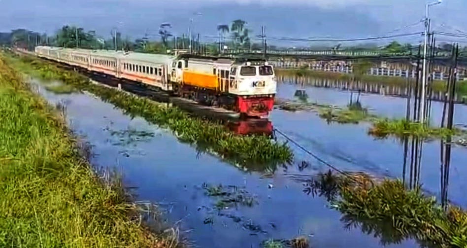 Salah satu rangkaian kereta api terlihat melintas pelan saat melewati banjir di potong, Sidoarjo, Selasa (17/6/2025). (Foto : Eleanor/tagarjatim.id)