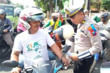 Anggota Satlantas Polrestabes Sidoarjo bagikan helm kepada pengendara yang tak memakai helm, Senin (14/7/2025). (Foto : Eleanor/tagarjatim.id)