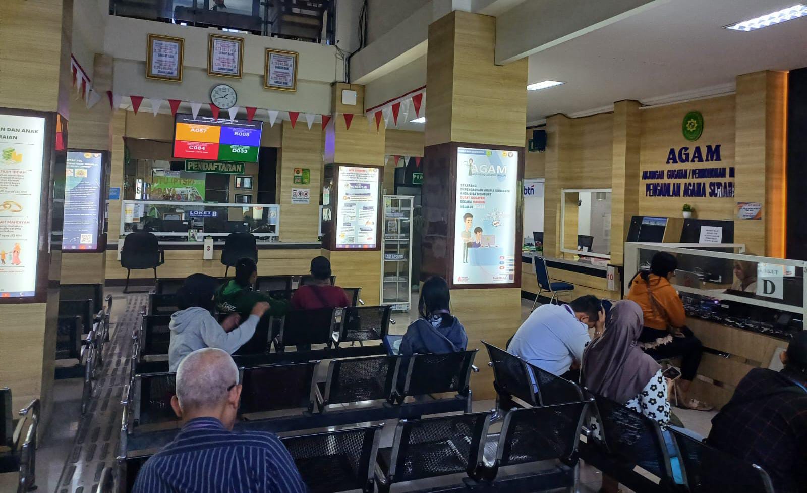 Sejumlah warga Surabaya dengan berbagai kepentingan tengah antre di loket layanan Pengadilan Agama, Senin (21/7/2025). (Foto : Eleanor)