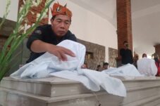 Tokoh masyarakat Desa Prasung, Bahrul Amig tengah mengganti kain kafan pembungkus nisan makam Mbah Sholeh, Minggu (13/7/2025). (Foto : Eleanor)